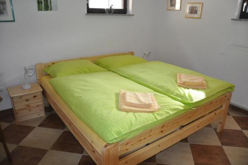 Una cama con sábanas verdes y dos toallas. en Privatzimmer Bendl en Steinhaus am Semmering