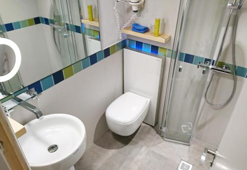 a bathroom with a shower and a toilet and a sink at Hotel Niedersachsen in Westerland (Sylt)
