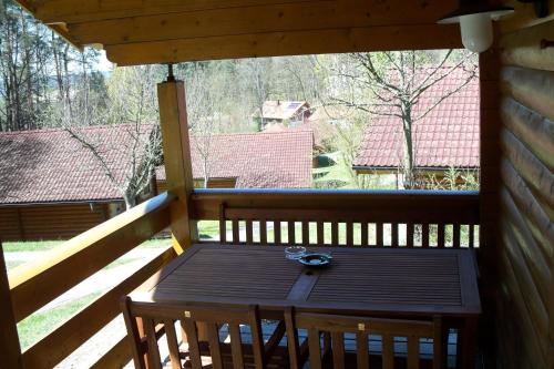 una mesa de madera en el porche trasero de una cabaña en Blockhaus Hedwig, en Stamsried