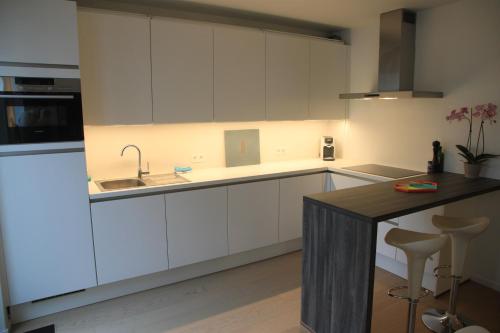 a kitchen with white cabinets and a black counter top at NEW Design apartment in Brussels in Brussels