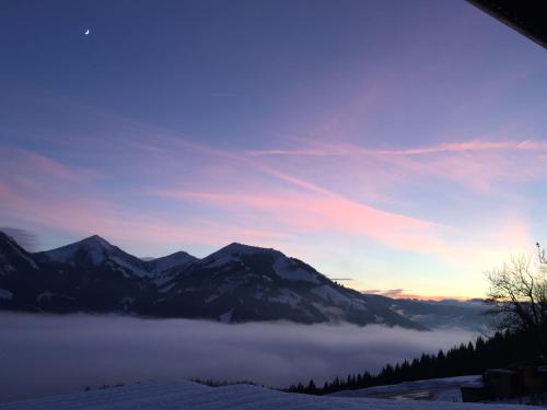 a view of a mountain range with a layer of clouds at Reiterbauer Chalets & Ferienwohnungen in Kirchberg in Tirol