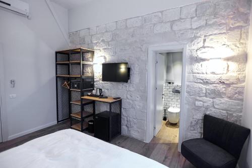 a bedroom with a stone wall with a bed and a desk at City Port Hotel in Haifa
