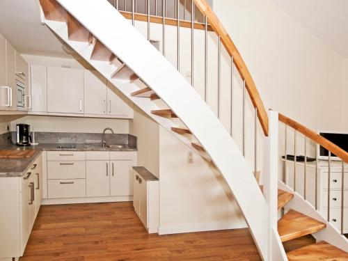 a kitchen with white cabinets and a wooden stairway at Flair Landhotel Strengliner Mühle in Pronstorf