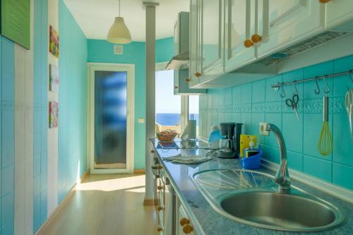 uma cozinha azul com um lavatório e uma janela em Piso Paraiso La Nea em Radazul