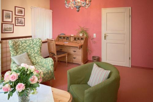 a living room with a desk and chairs and a vase of flowers at Pension Villa Edelweiß in Ostseebad Sellin
