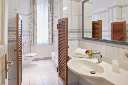 a bathroom with a sink and a toilet and a mirror at Pension Villa Edelweiß in Ostseebad Sellin