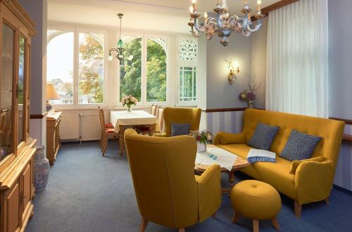 a living room with yellow chairs and a table at Pension Villa Edelweiß in Ostseebad Sellin