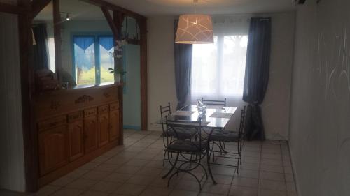 ein Esszimmer mit einem Tisch, Stühlen und einem Fenster in der Unterkunft la ferme aux kangourous in Donzy
