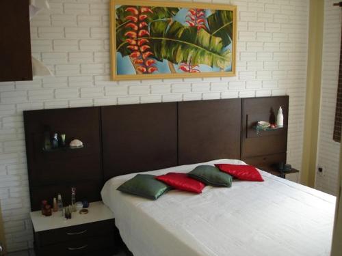 Schlafzimmer mit einem Bett mit roten und grünen Kissen in der Unterkunft Pousada Cheiro De Mar in Imbituba