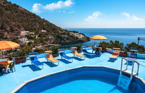 a swimming pool with chairs and umbrellas and the ocean at Le Terrazze sul mare in Ustica