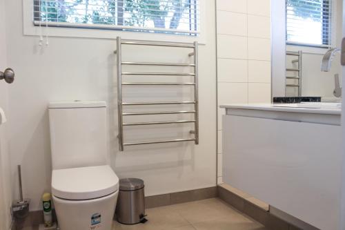 biała łazienka z toaletą i umywalką w obiekcie Amazing Kiwi Lodge w mieście Whangamata