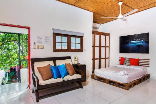 ein Schlafzimmer mit einem Bett, einem Sofa und einem TV in der Unterkunft La Puerta Roja Guest House in Santo Domingo