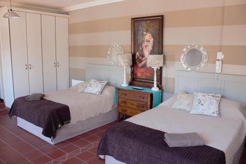 a bedroom with two beds and a painting on the wall at The Well guesthouse/Retreat in Kroonstad