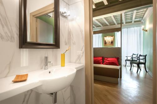 a bathroom with a sink and a mirror and a couch at Raffaello Charmsuite in Rome