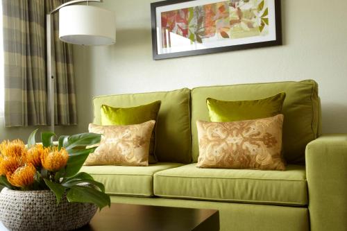 a green couch with pillows in a living room at Skyline Island Colony Hotel in Honolulu