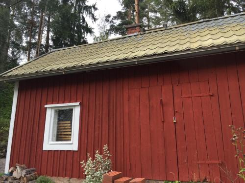 a red barn with a white window and a roof at Metsäranta House in Tammela