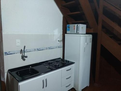 a small kitchen with a stove and a refrigerator at Pousada Farol do Arvoredo in Governador Celso Ramos