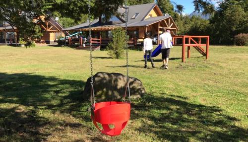 a swing in a yard with two people playing at Martina Bungalows in Ensenada