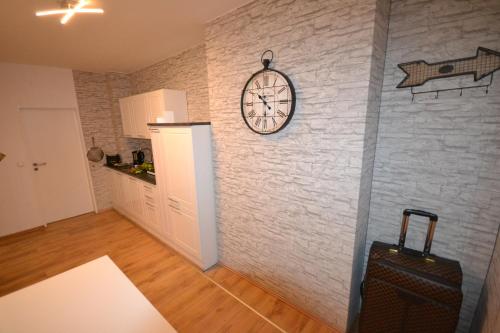 a room with a brick wall with a clock and a suitcase at Madame Tower in Cologne