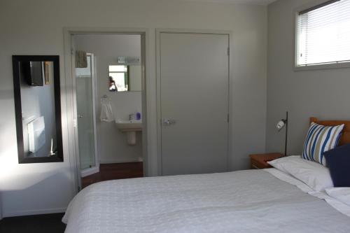 a bedroom with a bed and a bathroom with a sink at Pleasant View Bed & Breakfast in Timaru