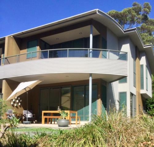 a large house with a balcony with a table in front of it at Boom 8 Boomerang Beach in Blueys Beach