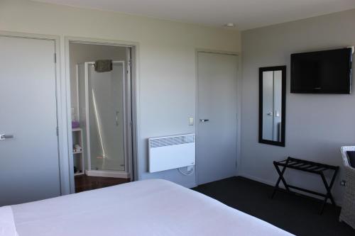 a bedroom with a white bed and a flat screen tv at Pleasant View Bed & Breakfast in Timaru