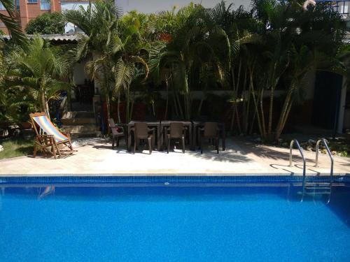 a pool with a table and chairs and palm trees at Hotel Boutique Casa Berastegui in Puerto Colombia
