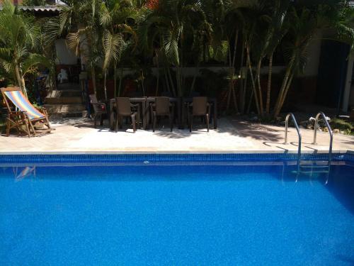 a swimming pool with chairs and a table and palm trees at Hotel Boutique Casa Berastegui in Puerto Colombia