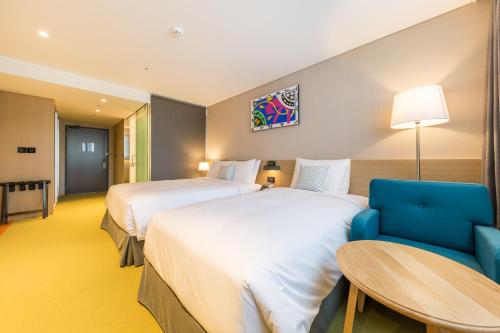 a hotel room with two beds and a blue chair at Howard Johnson by Wyndham Incheon Airport in Incheon