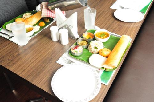 een tafel met twee dienbladen eten erop bij Hotel Somisetty Landmark in Rāzole