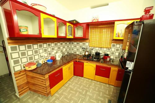 a small kitchen with red yellow and white cabinets at Arabian Nights Munnar Pool Villa in Munnar