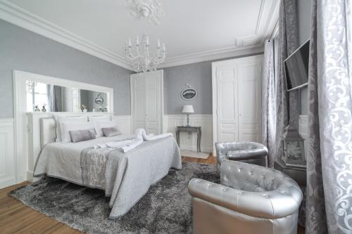 una camera da letto bianca con un letto e una sedia di La Demeure De Charme a Troyes