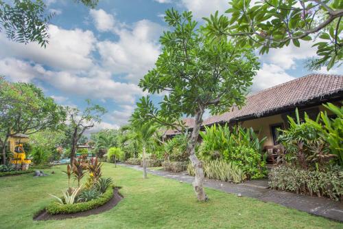 a garden with a building and trees and grass at Taruna Boutique Homestay & Spa in Pemuteran