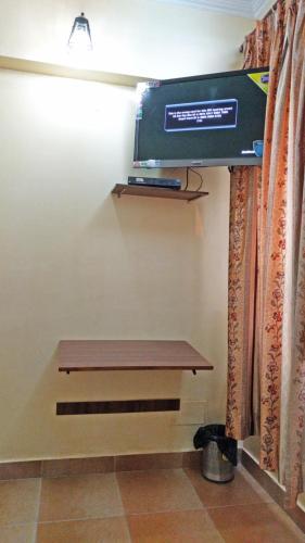 a bench in a room with a television on the wall at Hotel Rangoli in Jaipur