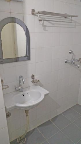 a white bathroom with a sink and a mirror at Hotel Rangoli in Jaipur