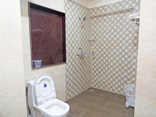 a bathroom with a toilet and a shower with a window at Hotel Rangoli in Jaipur