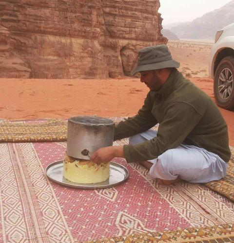 a man is cutting a cake in the desert at Climbers House in Wadi Rum in Wadi Rum