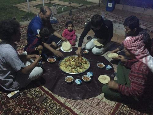 a group of people sitting around a table eating pizza at Climbers House in Wadi Rum in Wadi Rum