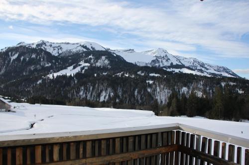 a view from the deck of a resort with snow covered mountains at Katharinahof Ferienpension in Sibratsgfäll