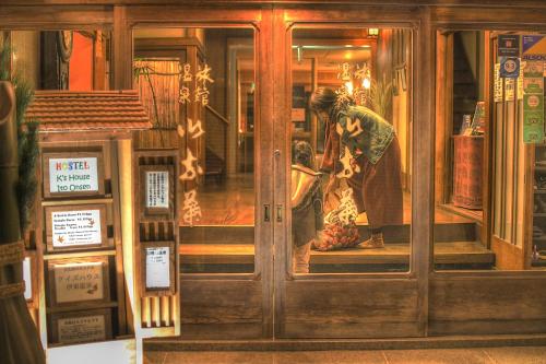 a woman looking in the window of a store at K's House Ito Onsen - Historical Ryokan Hostel in Ito