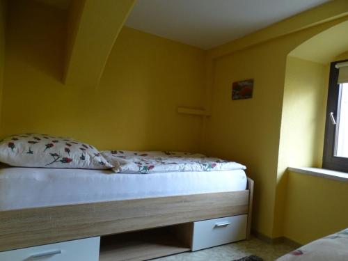 a bedroom with a bed with yellow walls and a window at Ferienwohnung Altstadt Löbau in Löbau