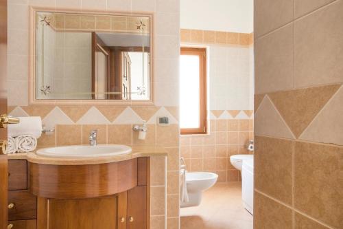 La salle de bains est pourvue d'un lavabo, de toilettes et d'un miroir. dans l'établissement Masseria Cappella, à Martina Franca