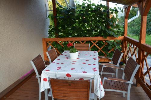 uma mesa com uma toalha de mesa branca com flores vermelhas num alpendre em Örömvölgy Vendégház em Bózsva