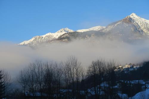 a mountain shrouded in fog with trees and mountains at Rooms Alpe Veglia-Varzo in Varzo