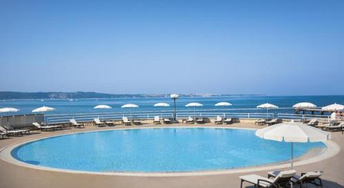 a pool with chairs and umbrellas and the ocean at Floating Sea House Portorose in Portorož
