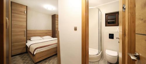 a small bathroom with a bed and a toilet at Pansion Winter in Jahorina