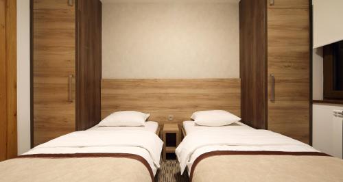 two beds in a room with wooden walls at Pansion Winter in Jahorina