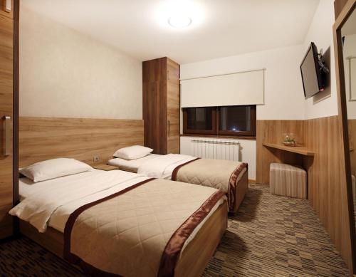 a hotel room with two beds and a television at Pansion Winter in Jahorina