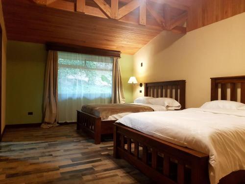 Un dormitorio con dos camas y una ventana. en Casa El Granero Monteverde, en Monteverde