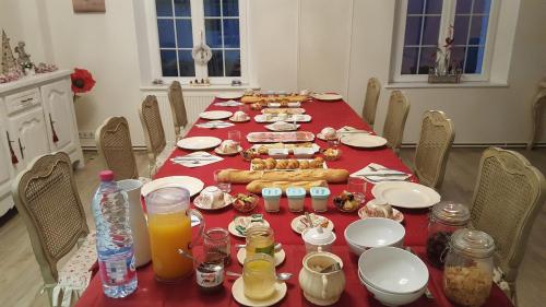 una mesa larga con un mantel rojo con comida y bebida en Un Parfum de Campagne, en Méaulte